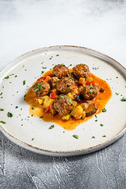 Delicious meatballs made from ground beef in tomato sauce, served in old metal pan. Gray background. Top view