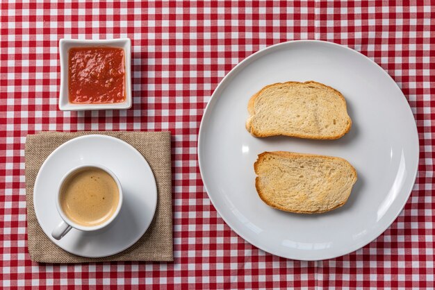 Deliziosa colazione mediterranea composta da toast con pomodoro e caffè, servita su una tovaglia scozzese vintage e un tovagliolo di tela. .