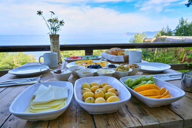 新鮮なフルーツやその他の栄養価の高い食べ物を揃えたおいしい地中海式朝食を、海を見渡すテーブルで提供し、幸福な雰囲気を作り出します