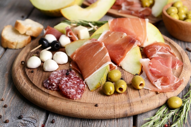 Delicious melon with prosciutto on table closeup