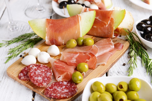 Delicious melon with prosciutto on table closeup