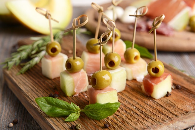 Delicious melon with prosciutto on table closeup