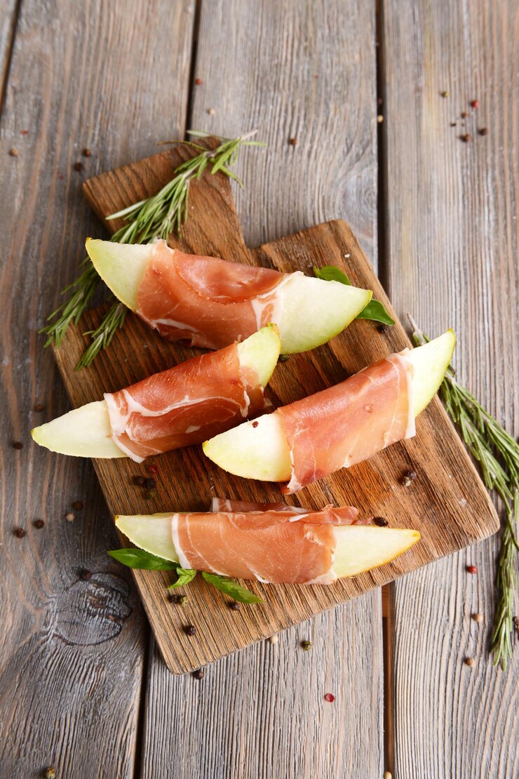 Photo delicious melon with prosciutto on table closeup