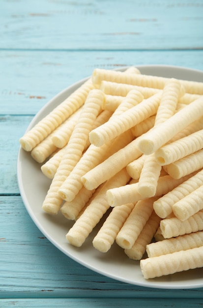 Delicious milk wafer rolls on blue background Vertical photo