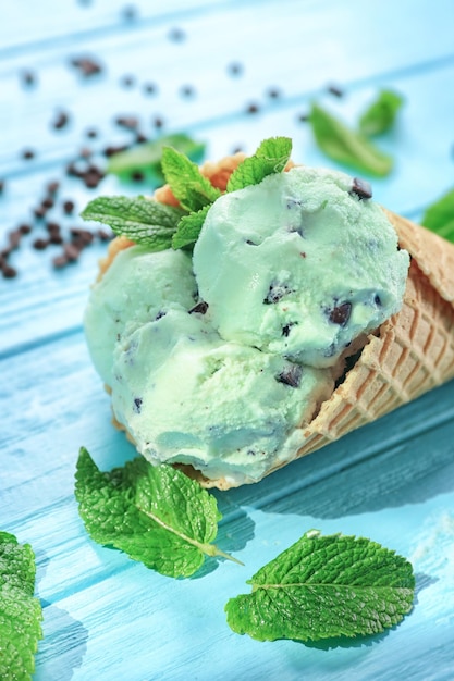Вкусное мятное шоколадное мороженое в вафельном рожке на деревянном фоне крупным планом