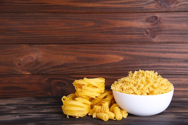 Delicious mixed pasta in bowl on a brown background