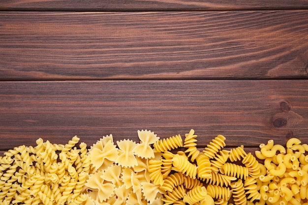 Delicious mixed pasta on brown background with copy space