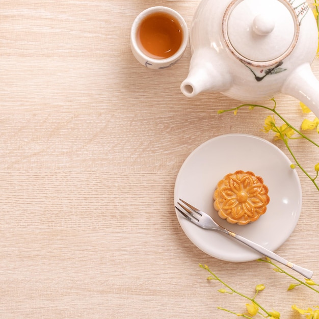 写真 黄色い花とお茶で飾られた美しい模様の中秋節のおいしい月餅お祭りの午後のペストリーのデザインのコンセプト