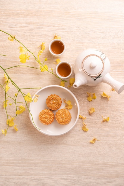 Delicious moon cake for Mid-Autumn festival with beautiful pattern, decorated with yellow flowers and tea