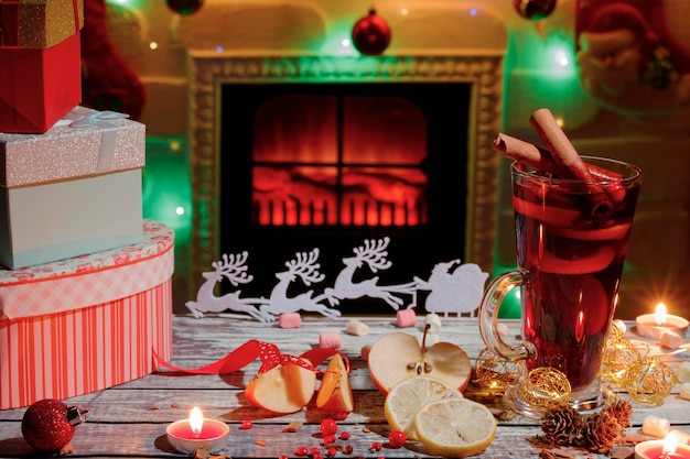 Delicious mulled wine Christmas decorations and gift boxes on the table Fireplace