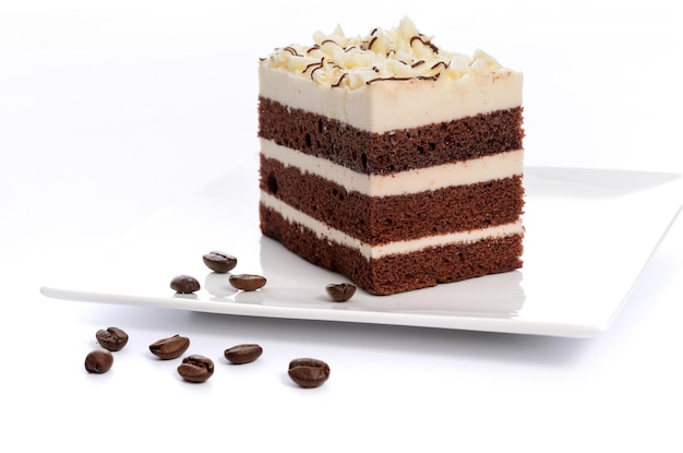 Delicious multilayer homemade coffee sponge cake with sugar mass on a saucer with roasted coffee beans closeup