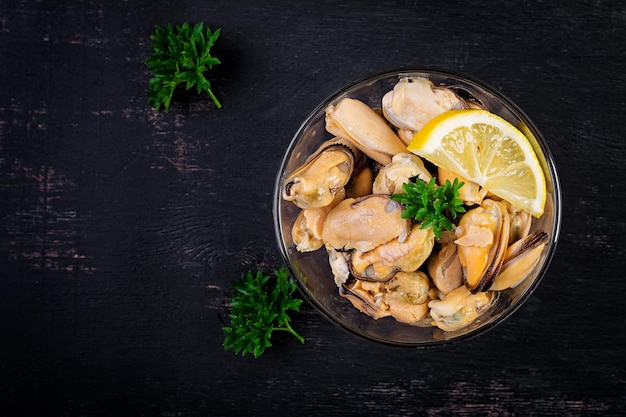 Deliziosa carne di cozze con limone e prezzemolo fresco su sfondo scuro vista dall'alto piatto