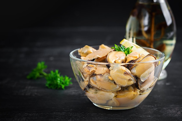 Delicious mussel meat with lemon and fresh parsley on a dark background