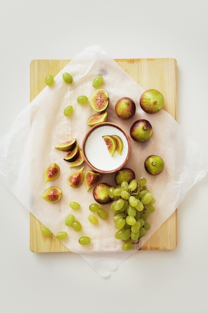 Delicious natural Greek yogurt in clay bowl with figs and grape