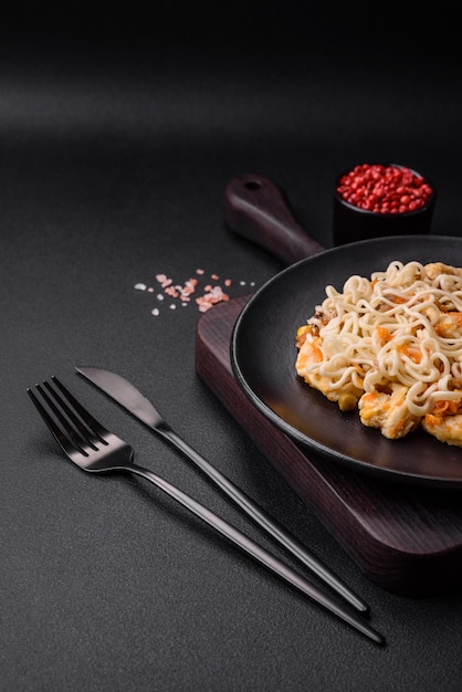 Delicious noodles with chicken and vegetables or udon on a black ceramic plate