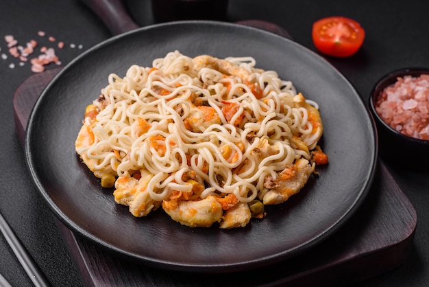 黒い陶器の皿に鶏と野菜のおいしい麺またはうどん