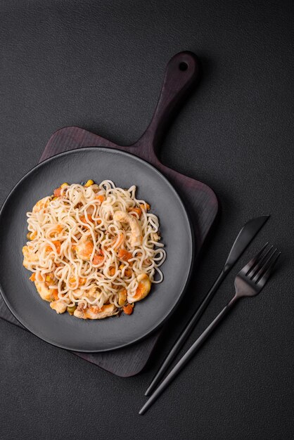 Delicious noodles with chicken and vegetables or udon on a black ceramic plate