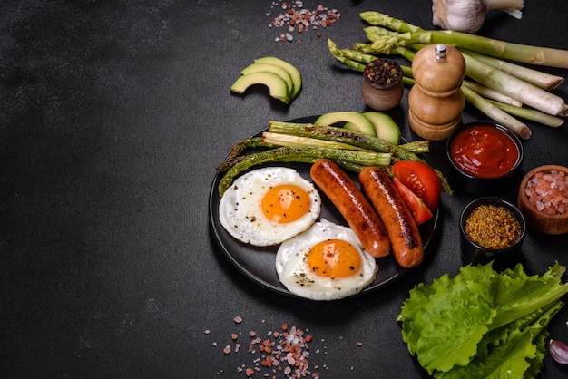 A delicious nourishing breakfast with fried eggs sausages asparagus tomatoes avocado spices and herbs