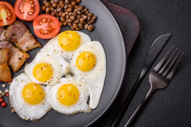 Delicious nutritious breakfast of fried quail eggs bacon legumes and cherry tomatoes