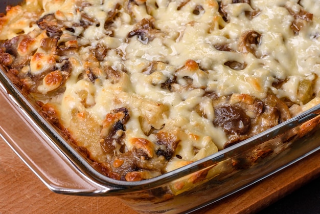 A delicious nutritious dish with meat mushrooms vegetables and\
potatoes baked in a creamy sauce in an oven