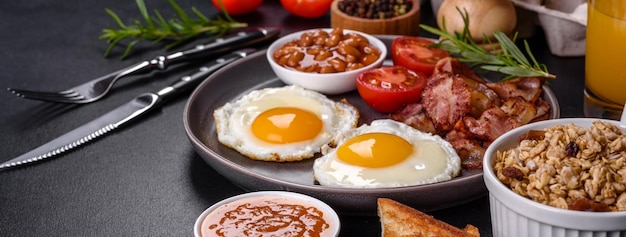 A delicious nutritious healthy breakfast with fried eggs bacon beans a glass of juice oat cookies milk and jam Healthy eating at the beginning of the day