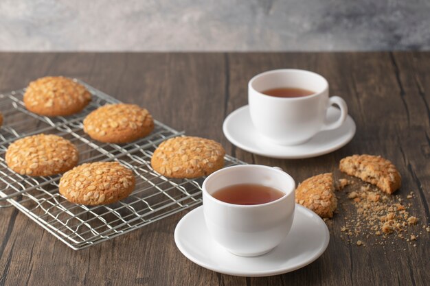 Delicious oatmeal biscuits and cups of hot tea on wooden table