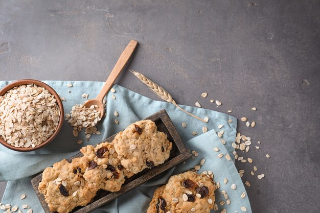 Delicious oatmeal cookies with raisins on grey textured table