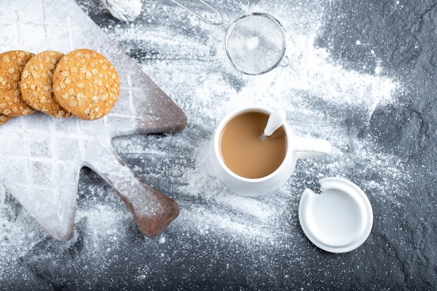 Delicious oatmeal cookies on wooden board with cup of hot coffee.