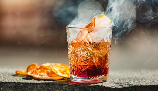 Delicious old fashion cocktail in the etched glass with ice and orange slices Shallow dof