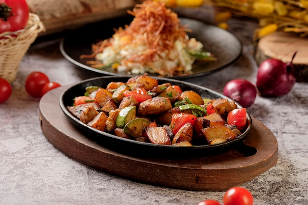 Foto deliziose patate al forno con erbe e verdure in padella, stile rustico. patate fritte, pomodorini rossi, zucchine, cipolla