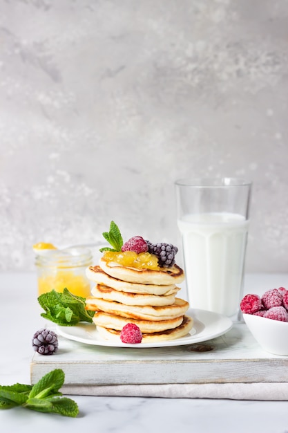 Delicious pancakes with berries and glass of milk