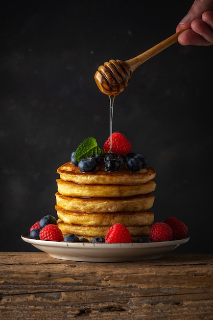 Photo delicious pancakes with fresh berries and dripping honey