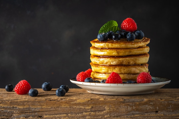 Delicious pancakes with fresh berries on rustic wooden table. Food concept.