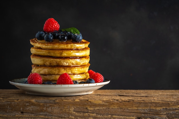 Delicious pancakes with fresh berries on rustic wooden table.