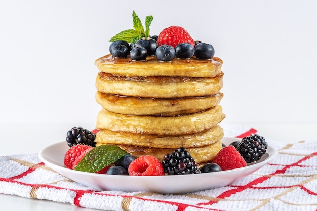 Delicious pancakes with fresh berries on white table