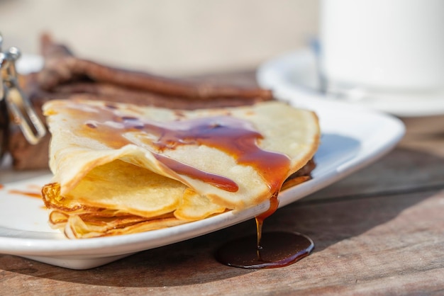 Delicious pancakes with mangrove honey and white cup of tea on the table close up