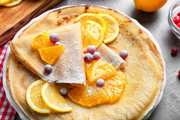 Delicious pancakes with orange and cranberry on plate