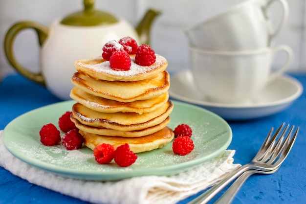 写真 テーブルにラズベリーとおいしいパンケーキとお茶のカップ