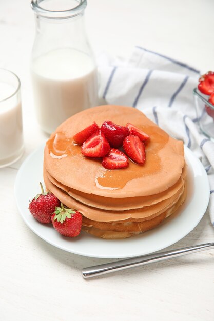 テーブルの上にイチゴと蜂蜜とおいしいパンケーキ