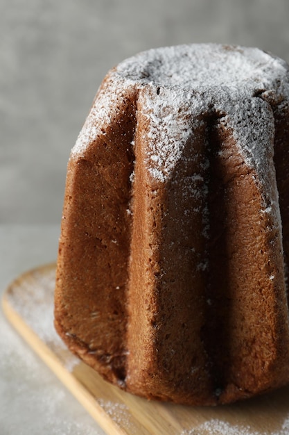 Delicious Pandoro cake decorated with powdered sugar on light grey table closeup Traditional Italian pastry