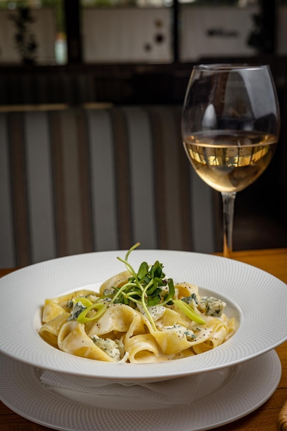 delicious pasta with cheese, greens, sauce in a restaurant