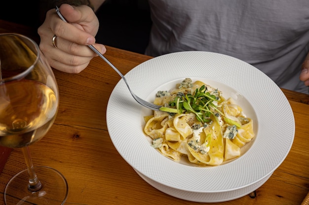 レストランでチーズ、野菜、ソースのおいしいパスタ