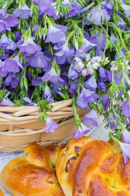 Delicious pastries (rolls with raisins) and bouquet linen in wicker basket