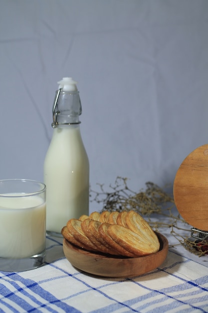 Foto deliziosa pasticceria su un piatto di legno con bottiglia di latte