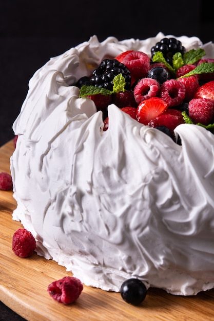 Foto deliziosa torta pavlova con meringa e frutti di bosco freschi su sfondo nero