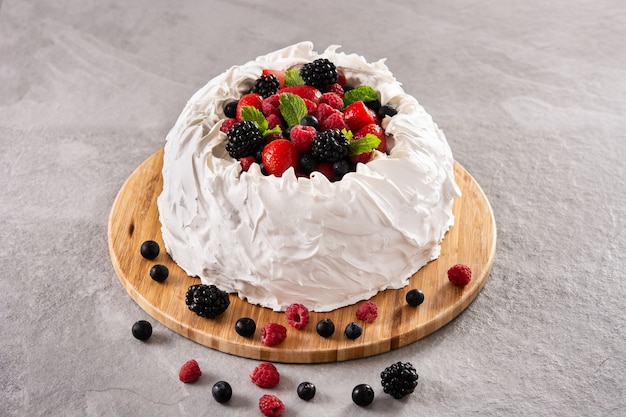 Delicious Pavlova cake with meringue topped and fresh berries on gray stone