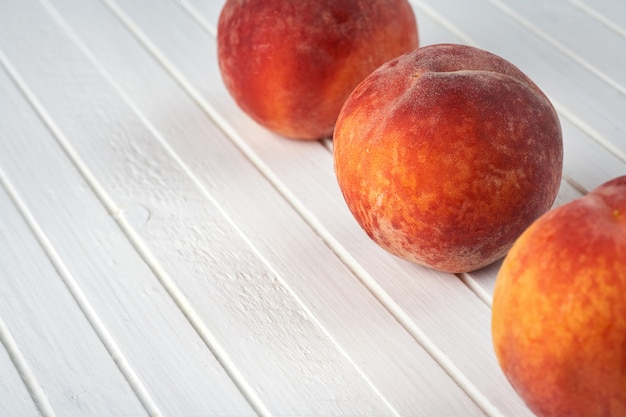 Delicious peaches on a white wooden background.