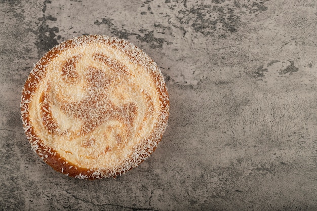 Delicious pie decorated with coconut sprinkles on stone table.