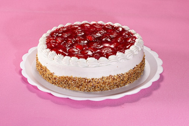 Delicious pie with peanuts and strawberry on a white plate on a pink textured background