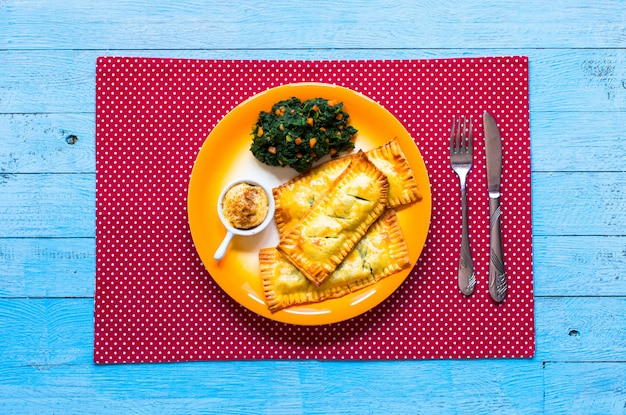 Delicious pie with spinach, made at home, on a wooden table